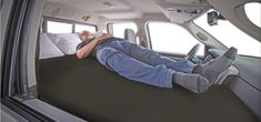 a man laying in the back seat of a car with his feet up and head down