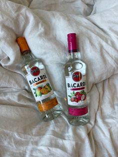 two bottles of bacardi on a bed