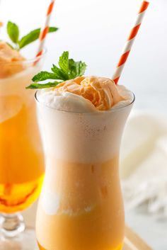 two glasses filled with drinks sitting on top of a table