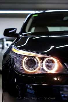 the front end of a black car with its lights on