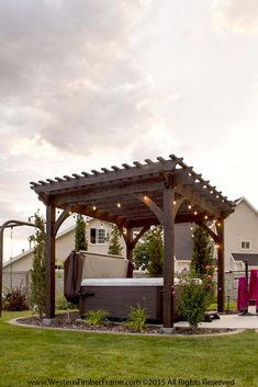 an outdoor hot tub in the middle of a yard with lights strung up on it