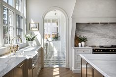 a kitchen with marble counter tops and an arched doorway leading to another room that has large windows