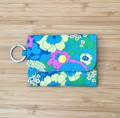 a blue and green flowered wallet with a metal keychain hanging from it