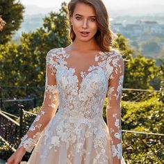 a woman wearing a wedding dress with long sleeves and flowers on the bouncy