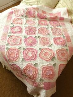 a pink and white quilt on top of a bed