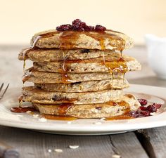 stack of pancakes with syrup and cranberries on plate