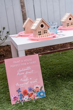 a table that has some little houses on it and a sign in front of it