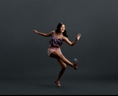 a young woman is dancing with her legs spread out in the air and holding a bottle