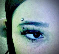 a woman with piercings on her eyes looking at the camera