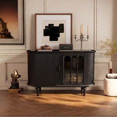 a living room with a black cabinet and pictures on the wall