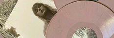 two pink records sitting next to each other on top of a wooden table with an image of a woman in the background