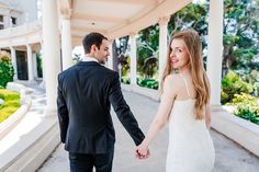 a bride and groom hold hands as they walk together