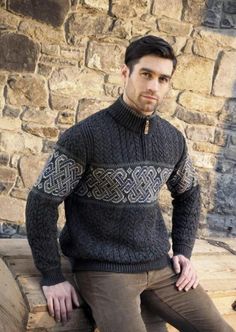 a man sitting on top of a wooden bench wearing a black sweater and brown pants