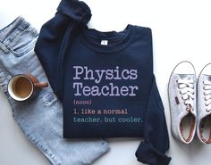 two pairs of shoes and a sweatshirt with the words physics teacher on it next to them