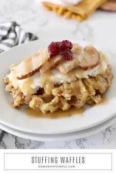 a white plate topped with waffles covered in gravy and cranberries