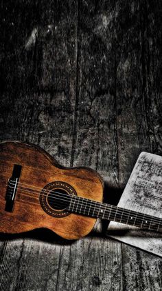 an acoustic guitar sitting on top of a wooden floor