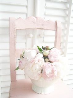 a white vase filled with flowers sitting on top of a pink chair