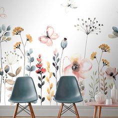 two blue chairs sitting in front of a wall with flowers and butterflies painted on it