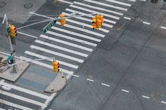 an overhead view of a street intersection with traffic lights on the corner and people walking across the crosswalk