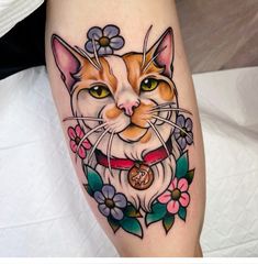 an orange and white cat with flowers around it's face on the leg,