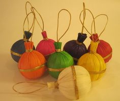 six different colored paper balls tied together with twine and gold string on white background