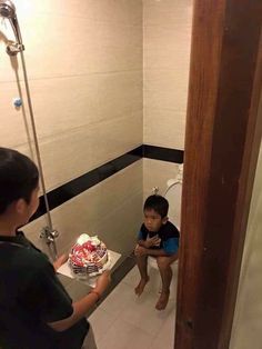 a young boy sitting on the toilet in front of a birthday cake