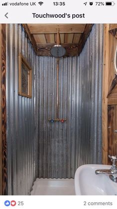 a bathroom with a metal shower stall and sink in the corner, next to a wooden paneled wall