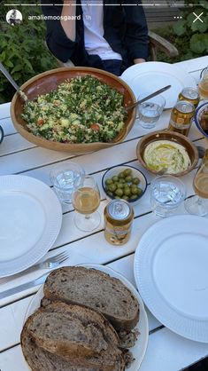 a table topped with plates and bowls filled with food on top of a white table cloth