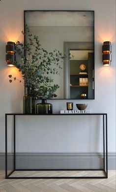 a mirror and some plants on a shelf in a room with white walls, wood floors and flooring