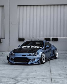 a blue sports car parked in front of a garage door with the words honda tires on it