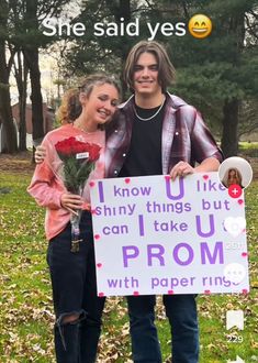 a man and woman standing next to each other holding a sign