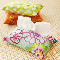 three colorful pillows and two tissues on a bed