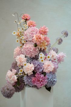 a white vase filled with lots of pink and purple flowers