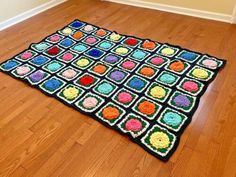 a multicolored crocheted rug on the floor in a room with hard wood floors