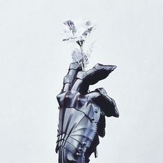 a statue holding a flower in its hand with the sky in the backgroud