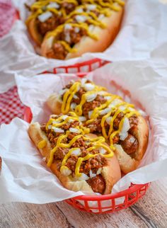 two chili cheese dogs in red baskets on a table