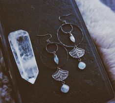 "Bohemian dangle earrings made from hammered gunmetal hoops, leaf charms, and rainbow moonstone spikes and bezel drops. They measure approximately 4\" long." Bohemian Labradorite Hand Forged Earrings, Gunmetal Earrings, Bohemian Rainbow, Edgy Jewelry, 2024 Trends, Boho Rainbow, Leaf Charms, Jewelry Inspo, Charm Earrings