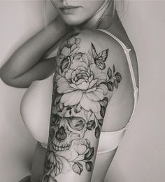 a woman's arm with flowers and skulls tattooed on the upper half of her body