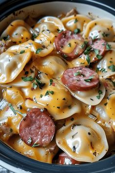 a crock pot filled with pasta and sausage covered in cheese, sauce and herbs