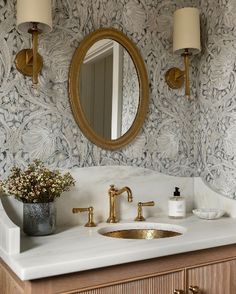 a bathroom sink with a mirror above it and a gold faucet next to it