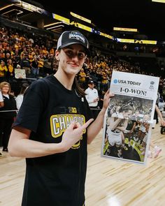 a young man holding up a newspaper in front of a crowd at a basketball game