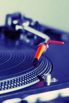 a turntable with a red and yellow object on it's side, in front of a white wall