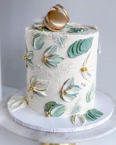 a wedding cake decorated with green leaves and gold decorations