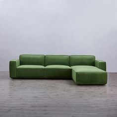 a green couch sitting on top of a hard wood floor next to a white wall