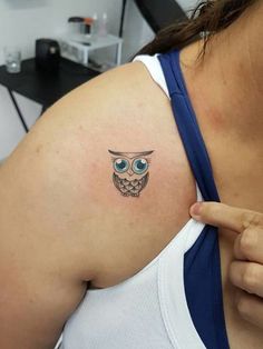 an owl tattoo on the back of a woman's left shoulder is shown in this image