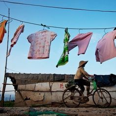 a man riding a bike past clothes hanging on a line