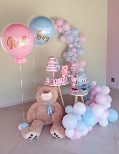 a teddy bear sitting in front of a cake and balloons on a table with other decorations