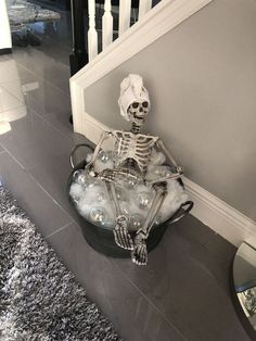 a skeleton sitting in a bucket filled with bubbles on top of a carpeted floor