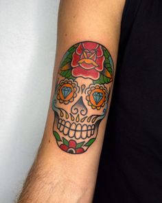 a man's arm with a colorful sugar skull tattoo on it