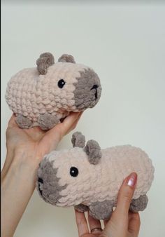 two stuffed animals are being held up by someone's hand with their thumb on them